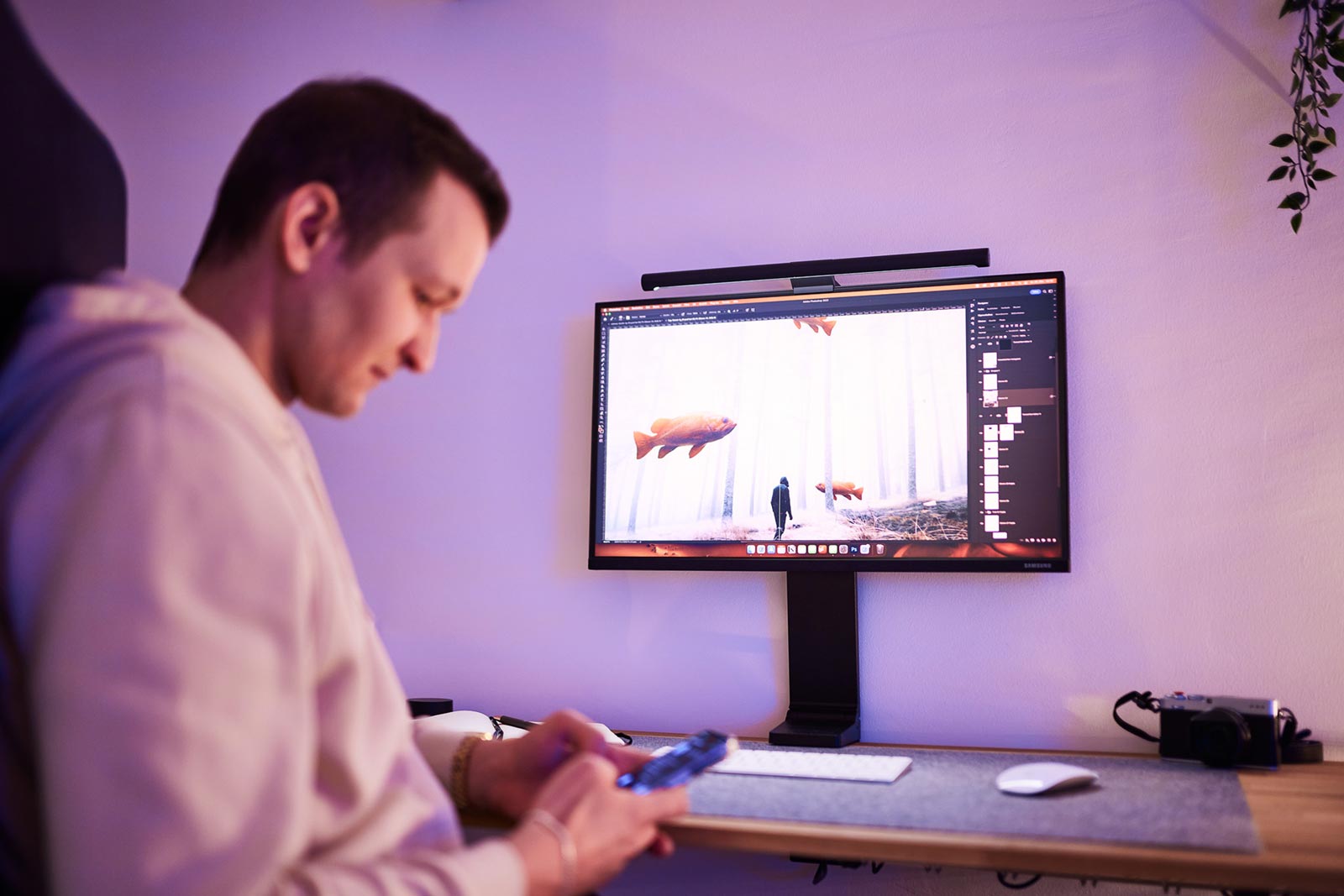Lukas Zischke am Schreibtisch, auf dem Monitor eine Bildmontage in Photoshop